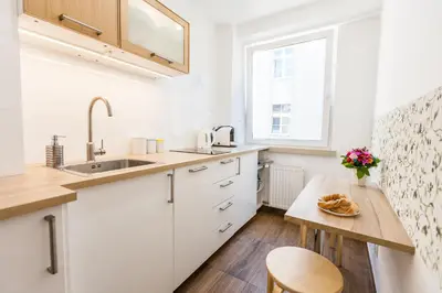 a kitchen with white cabinets and a wooden table at Vintage Tomasza 25 Apartments in Kraków