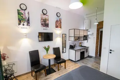 a living room with a table and chairs and a kitchen at Green - Apartamenty Kleparskie in Kraków