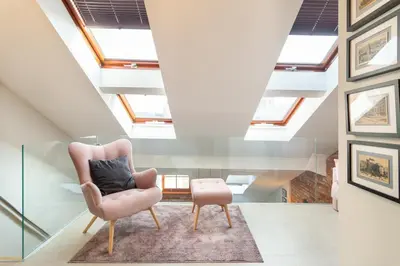 a living room with skylights and a chair at St Thomas Residence Old Town in Kraków