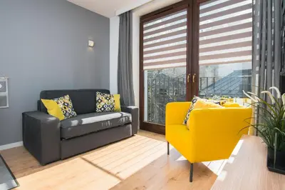a living room with a couch and a yellow chair at Horizon Apartments - Krowoderska in Kraków