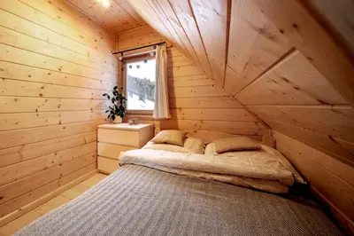 a bed in a wooden room with a window at Gorczańskie Siedlisko in Ochotnica Górna