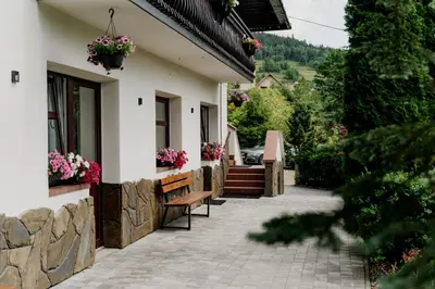 a house with benches and flowers on the side of it at Dom Wypoczynkowy U STASKA in Ochotnica Dolna