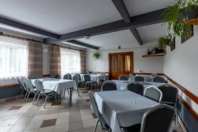 a dining room with tables and chairs and windows at Dom Wypoczynkowy U STASKA in Ochotnica Dolna