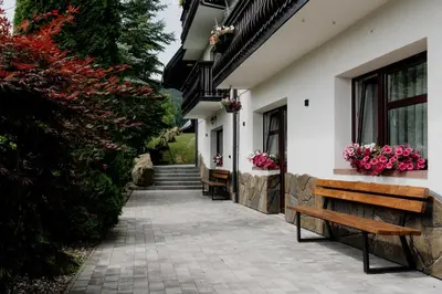 a bench next to a building with flowers on it at Dom Wypoczynkowy U STASKA in Ochotnica Dolna