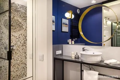 a bedroom with a blue bed and a kitchen at Fragola Apartments Vistula View in Kraków