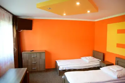 a room with two beds and an orange wall at Kompleks Rekreacyjno-Wypoczynkowy i Restauracja STRUMYK in Jordanów