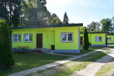 a small yellow and green house in a yard at Kompleks Rekreacyjno-Wypoczynkowy i Restauracja STRUMYK in Jordanów