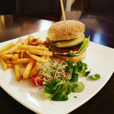 a white plate with a hamburger and french fries at Dworek Złoty Róg Hotel i Restauracja in Kraków