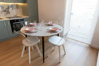 a dining room table with four chairs and a white table at Apartamenty na Wzgórzu in Bochnia