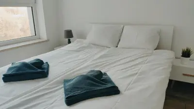 a white bed with two blue towels on it at Dąbska 26 by Homeprime in Kraków
