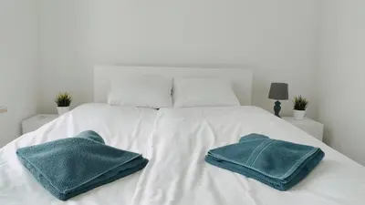 a white bed with two blue towels on it at Dąbska 26 by Homeprime in Kraków