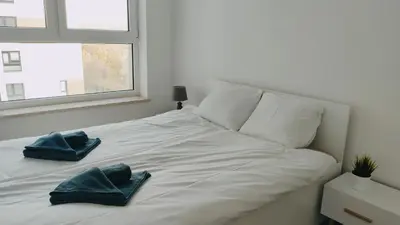 a white bed with two blue towels on it at Dąbska 26 by Homeprime in Kraków