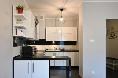 a kitchen with white cabinets and a black counter top at D&A Apartments Pawia in Kraków