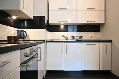 a white kitchen with white cabinets and a sink at D&A Apartments Pawia in Kraków