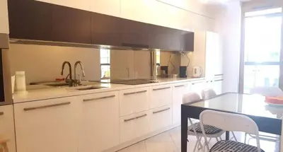 a kitchen with white cabinets and a black counter top at Apartment on the Boulvard in Kraków