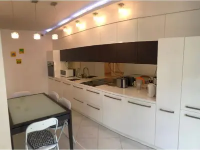 a kitchen with white cabinets and a table with chairs at Apartment on the Boulvard in Kraków