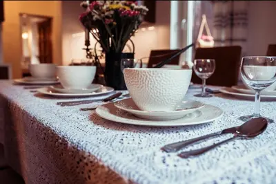 a table with plates and cups on a white table cloth at Dom Pod Lasem 44 in Klecza Górna