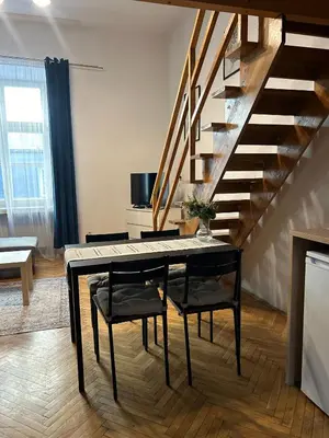 a dining room with a table and chairs and a staircase at VINTAGE SZPITALNA APARTMENT in Kraków