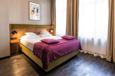 a hotel room with a bed with purple sheets and pillows at Liebeskind Boutique Hotel Old Town in Kraków