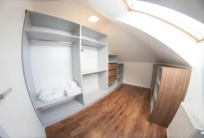 an attic room with a staircase with white shelves at Willa pod Lanckoroną in Izdebnik