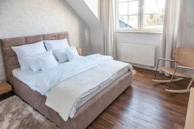 a bedroom with a large bed with white sheets and pillows at Willa pod Lanckoroną in Izdebnik