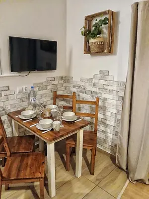 a wooden table with chairs and a television on a wall at Eleonor Accommodation exclusive house in Liszki