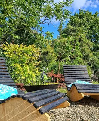 two wooden benches sitting in a garden with trees at Eleonor Accommodation exclusive house in Liszki