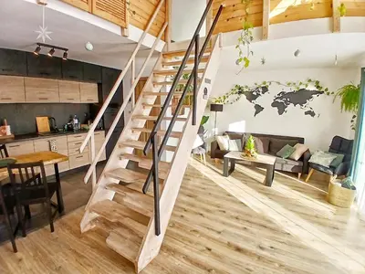 a wooden staircase in a living room with a world map on the wall at Eleonor Accommodation exclusive house in Liszki