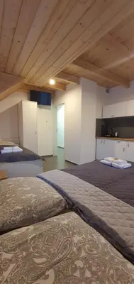 two beds in a large room with wooden ceilings at Dom Pod Groniem in Rzyki