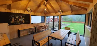 an empty restaurant with wooden benches and a chalkboard on the wall at Dom Pod Groniem in Rzyki
