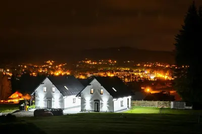 a white house on a hill at night at Domki Pod Lasem MM in Rabka