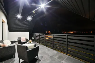 a balcony with a view of the city at night at Domki Pod Lasem MM in Rabka