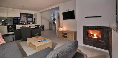 a living room with a fireplace and a kitchen at Domki Pod Lasem MM in Rabka