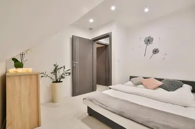 a white bedroom with two beds and a mirror at Domki Pod Lasem MM in Rabka