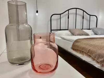 a vase and a glass bottle on a table next to a bed at Duo 1 Debniki Cozy Kraków Base 10-min to Wawel & Kazimierz Fast Wi-Fi in Kraków