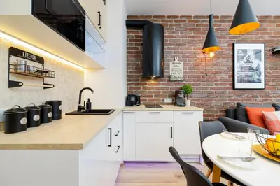 a kitchen with white cabinets and a brick wall at Cosy Apartment at the Main Station by Noclegi Renters in Kraków