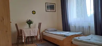 a room with two beds and a table and chairs at Centro Unita in Kraków