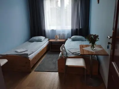 a bedroom with two beds and a table and a window at Centro Unita in Kraków