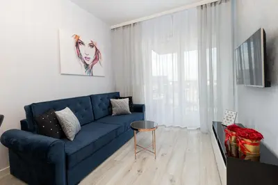 a living room with a blue couch and a window at Angel Apartments 1 in Kraków