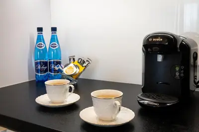 two cups of coffee on a counter next to a coffee maker at Angel Apartments 1 in Kraków