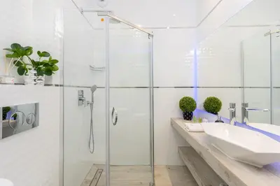 a bathroom with a glass shower and a sink at Angel Apartments 2 in Kraków