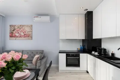 a kitchen with white cabinets and a table with pink roses at Angel Apartments 2 in Kraków