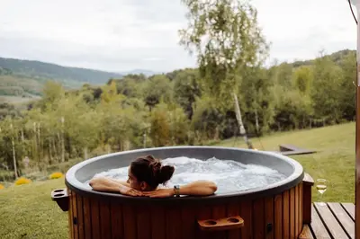 a woman laying in a hot tub in a field at CzillChata - dom z balią in Maków Podhalański
