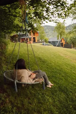 a woman sitting in a swing in the grass at CzillChata - dom z balią in Maków Podhalański