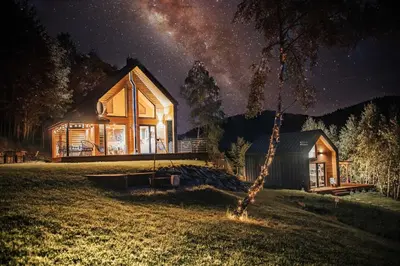 a wooden house on a field at night at CzillChata - dom z balią in Maków Podhalański