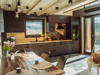 a kitchen with a wooden table and a dining room at CzillChata - dom z balią in Maków Podhalański