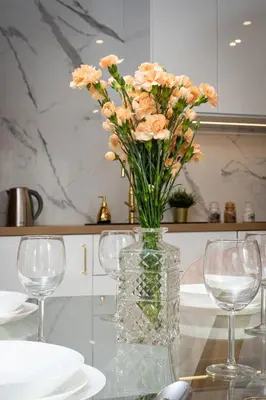 a vase of flowers sitting on a table with two glasses at Glossy Apart G9 in Kraków