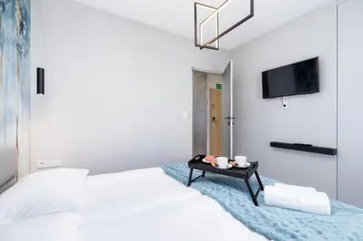 a white bedroom with two beds and a tv at Mogilska Apartments by Renters Prestige in Kraków