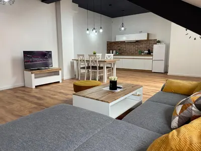 a living room with a couch and a table and a kitchen at Apartament Rynek 13 z parkingiem - Centrum Bochni in Bochnia