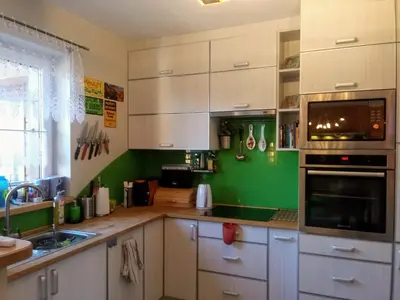 a kitchen with white cabinets and a green wall at Chata Mego Brata in Limanowa